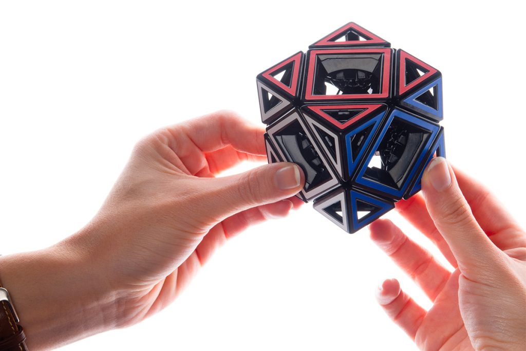 Person holding a geometric puzzle toy with red, blue, and black colors